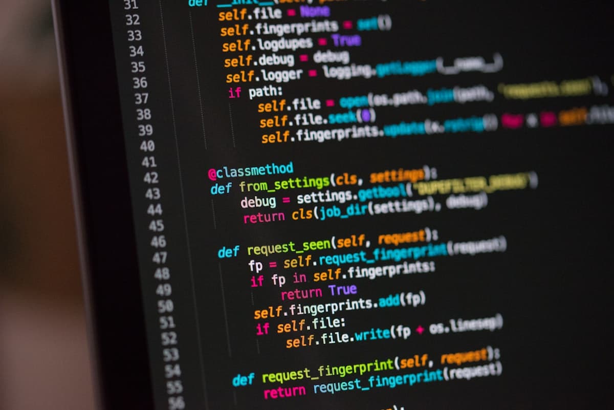 Linhas de código-fonte em close-up na tela de um computador, representando o código gerado e revisado por equipes de desenvolvimento